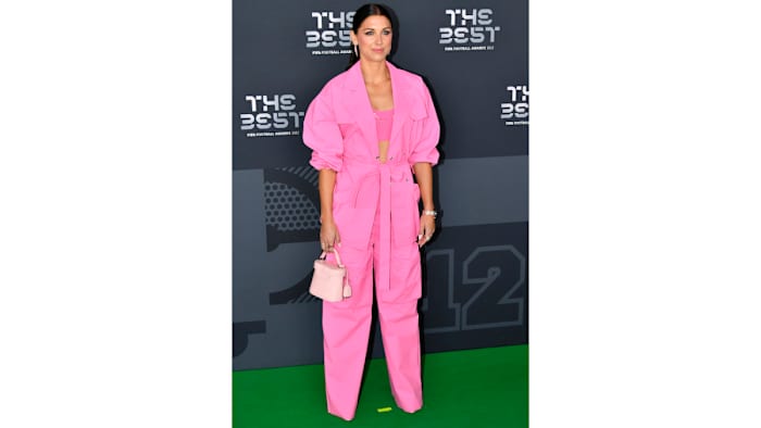 Alex Morgan poses on a red carpet in a hot pink suit and bralette.